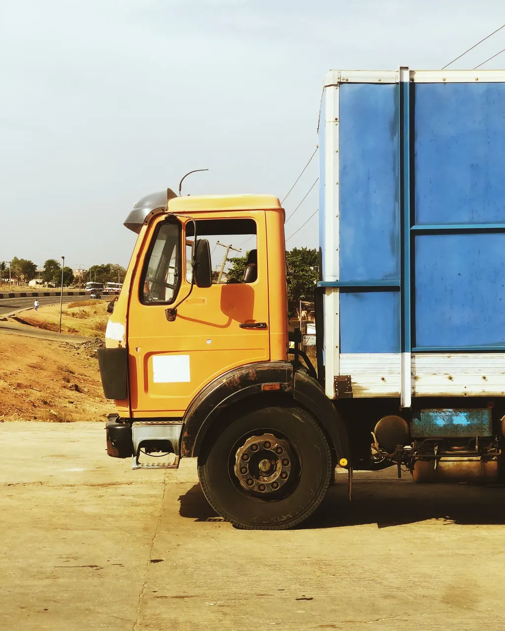 Orange and blue commercial truck on a Nigerian road
